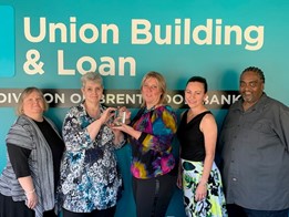 Union Building and Loan employees posing in front of bank logo.