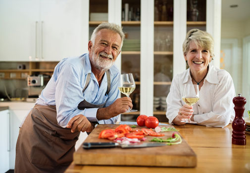Senior citizens enjoying a glass of wine in their kitchen
