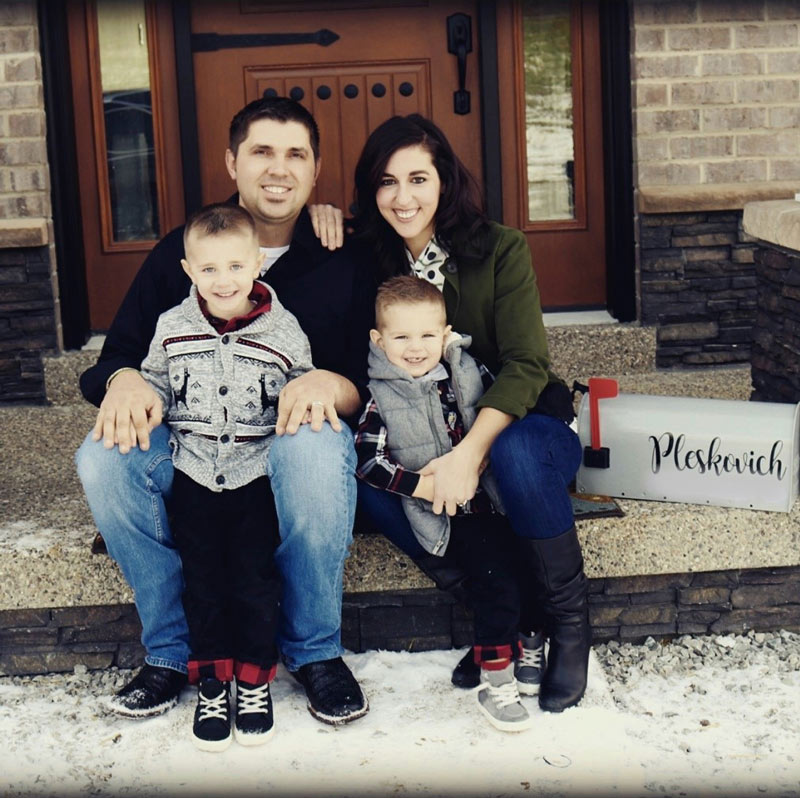 Family sitting on porch of their new home funded by residential construction loan